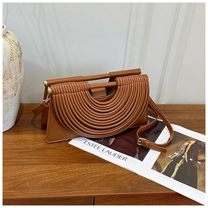 Vue détaillée du sac à bandoulière marron avec plis design sur surface en bois