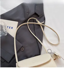 Detailed shot of cream-colored pebble leather bag with cute cat charm on office desk