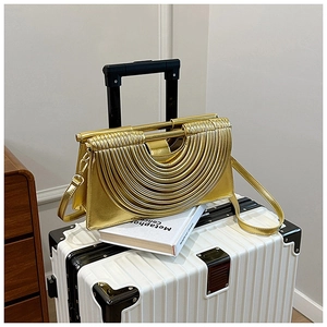 Détail d'un sac à main doré métallisé avec texture plissée sur une valise