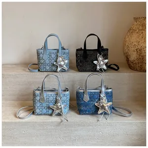 Detailed view of four denim-style bucket bags with star pendants on stone steps