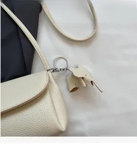 Detail of off-white lychee grain leather shoulder bag with a cute elephant charm