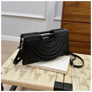 Détail du design plissé architectural sur un sac à bandoulière noir élégant en cuir