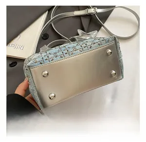 Detail view of denim bucket bag base with silver mirror material and metal protective studs
