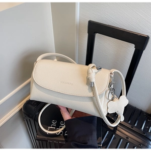 Detail of cream lychee leather underarm bag with knot strap and elephant charm