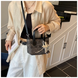Detail of grey plaid bucket bag with a silver star pendant and black leather strap
