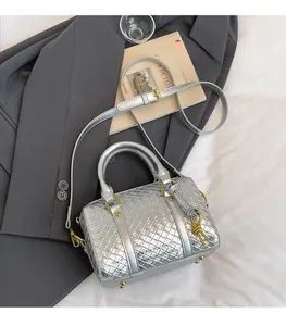 Detail of silver woven Boston bag with top handles, gold hardware, and long shoulder strap