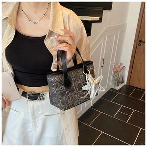 Detail of tweed bucket bag with silver tinsel texture and star charm accessory