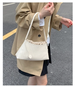 Detail of cream woven leather shoulder bag with drawstring inner pouch in street style