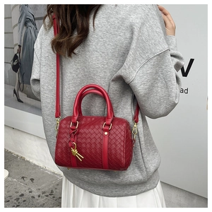 Detail of red woven leather Boston bag with gold knotted charm and shoulder strap