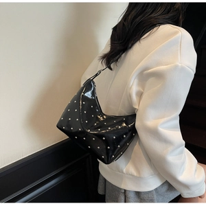 Detail view of stylish black rivet hobo bag showing the silver studs and shoulder strap