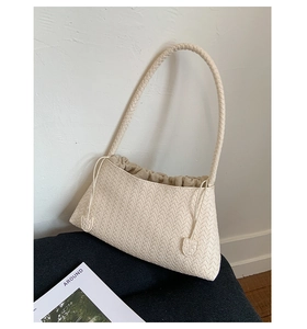 Detailed view of the beige woven leather strap and intricate texture of the shoulder bag