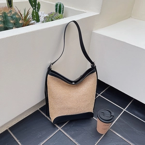 Minimalist woven straw underarm bag with black leather trim and shoulder strap