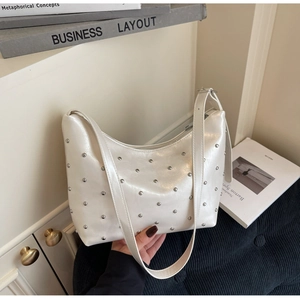 Detail of pearl white leather underarm bag with silver rivet studs and sleek silhouette