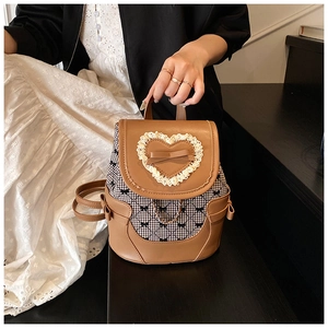 Détail d'un mini sac à dos en cuir marron avec cœur en dentelle et tissu à carreaux