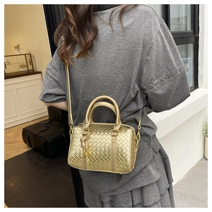 Macro detail of hand-woven gold Boston bag with metallic texture and sleek shoulder strap