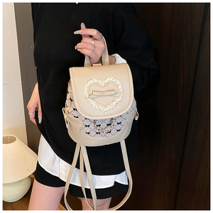 Détail d'un mini sac à dos beige avec dentelle en cœur, nœud et motif vichy noir