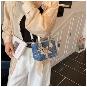 Detail view of blue denim handbag with silver trim and cute balloon dog charm accessory