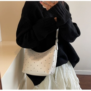 Detail of white hobo bag featuring silver metal rivets and elegant crescent moon design