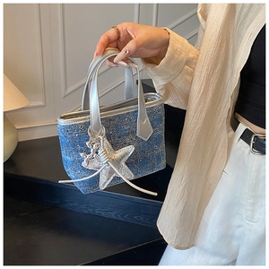 Detail of blue denim mini bag featuring gold metallic studs and star pendant in hand
