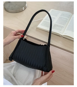 Detailed view of black woven leather handbag showing classic intrecciato texture and handle
