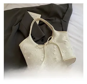 Detail of off-white floral tote bag with 3D flower decor and bow on grey suit background