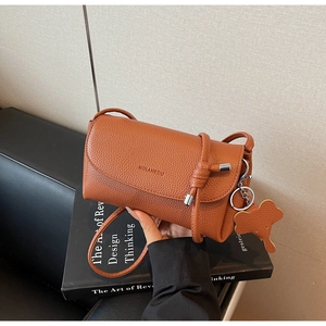 Brown lychee leather shoulder bag featuring decorative elephant charm and flap closure