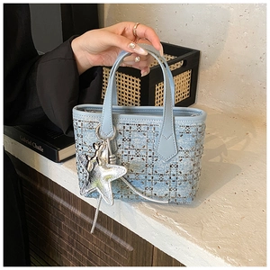 Detail of light blue denim mini tote with silver studs, star and balloon dog charms