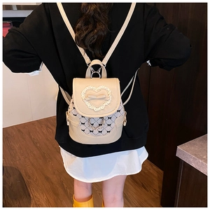 Détail d'un mini sac à dos crème avec bordure en dentelle cœur et nœud élégant