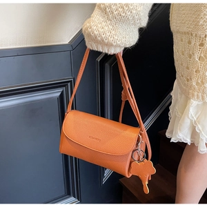 Detail of orange pebble leather shoulder bag with elephant charm and brand logo