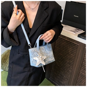 Light blue tweed bucket bag with star pendant shown on model in a stylish interior