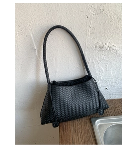 Detailed view of black woven leather handbag showing intricate texture and drawstring liner