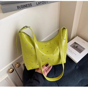 Close-up of bright neon green shoulder bag with silver rivets and metal zipper closure