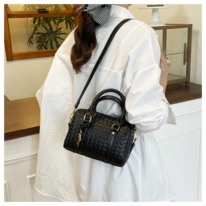 Detail of woven leather texture on a black Boston bag with gold-tone hardware and straps
