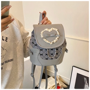 Detail view of mini backpack featuring grey leather, plaid fabric, and lace heart