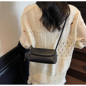 Detail of black pebbled leather crossbody bag on model with cute animal charm