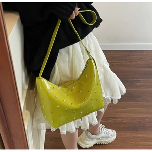 Detail showing shiny lime green patent leather shoulder bag with silver metal rivets