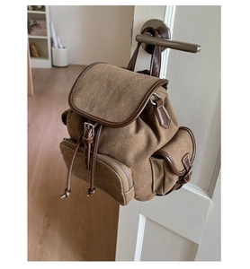 Detail of vintage canvas backpack with leather trim and buckle on a white door