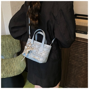 Close-up of light blue mini bucket bag with retro jacquard weave and star charm detail