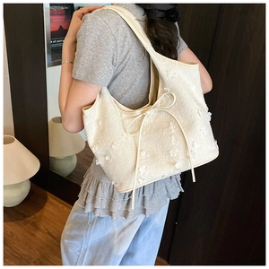 Detailed texture of off-white tote bag with 3D floral appliqués and sweet bow accents
