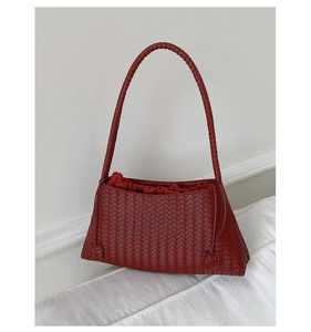 Detail of burgundy woven shoulder bag featuring premium leather texture and drawstring liner