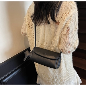 Detail of black lychee grain leather underarm bag featuring a cute dog charm and logo