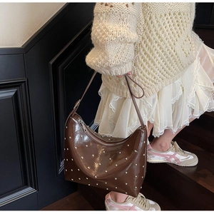 Close-up of retro dark brown patent leather shoulder bag with silver rivet details