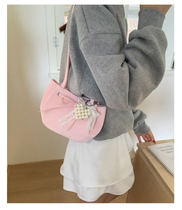 Rosa Schultertasche mit Spitze, Schleife und Perlenherz-Anhänger am Modell