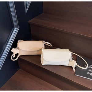 Detail of minimalist pebble leather crossbody bags with embossed logo and leaf charms