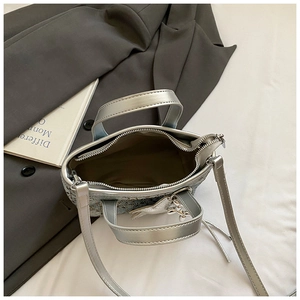 Detailed interior view of a silver tweed bucket bag with a brown lining and leather strap