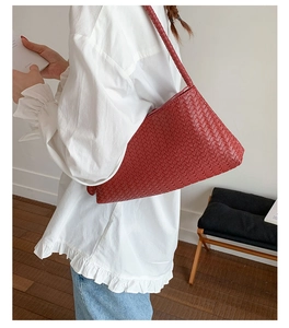 Close-up of deep red woven shoulder bag with intricate leather texture and braided strap