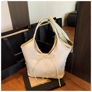 Detailed macro view of cream tote bag with 3D floral texture and delicate bow detail