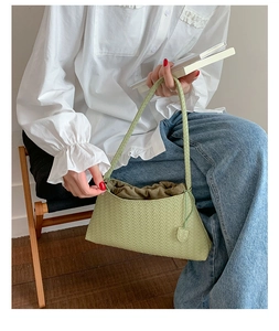Detail of light green woven hobo bag with a drawstring inner pouch on wooden floor