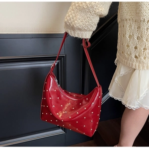 Detail of red patent leather shoulder bag with silver studs and metal zipper closure