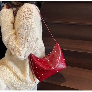 Close-up of bright red patent leather underarm bag with silver studs and zipper detail